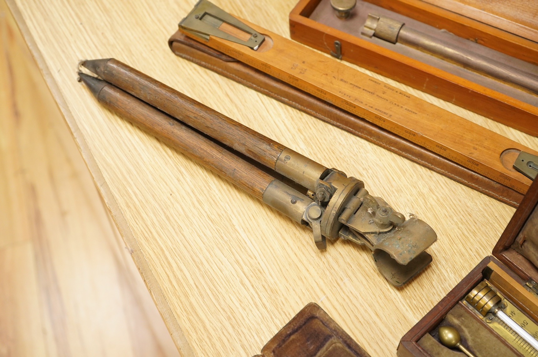Five scientific instruments, comprising; a rolling parallel rule, pine boxed, 48cm wide; an early 20th century boxwood and brass Alidade, by J. Hicks, 8, 9 & 10, Hatton Garden, leather cased; an oak and brass tripod, sta